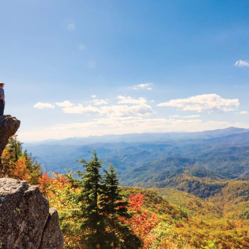 Man walking on the edge of a cliff high above the mountains
